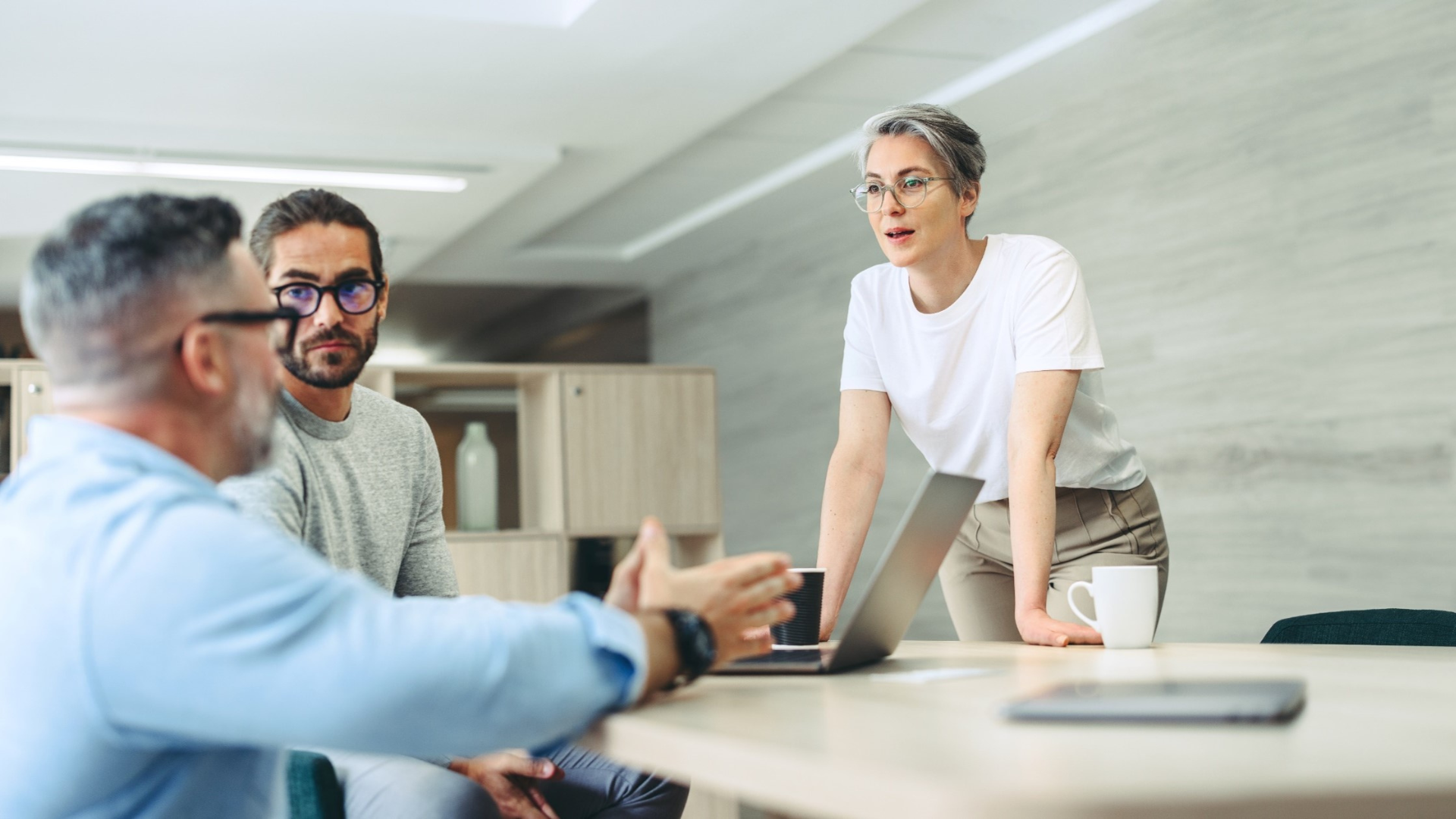 Team discussing strategy around a laptop in a modern office—representing operating model design and transformation planning