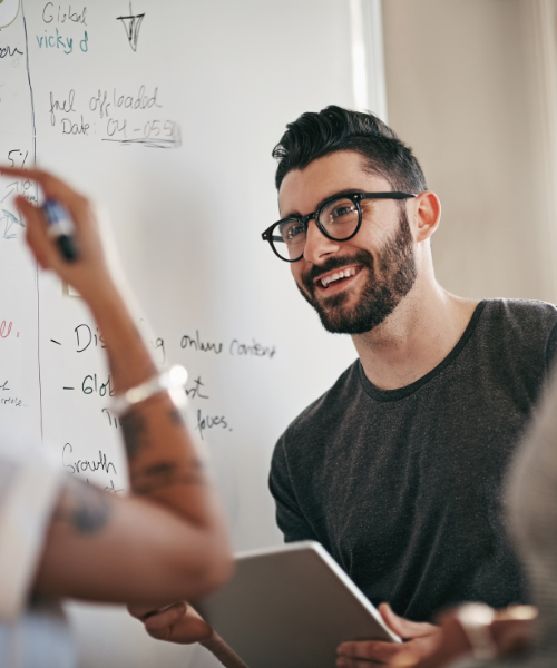 Consultant leading a planning session at a whiteboard—representing governance, regulatory alignment, and structured compliance in public sector delivery