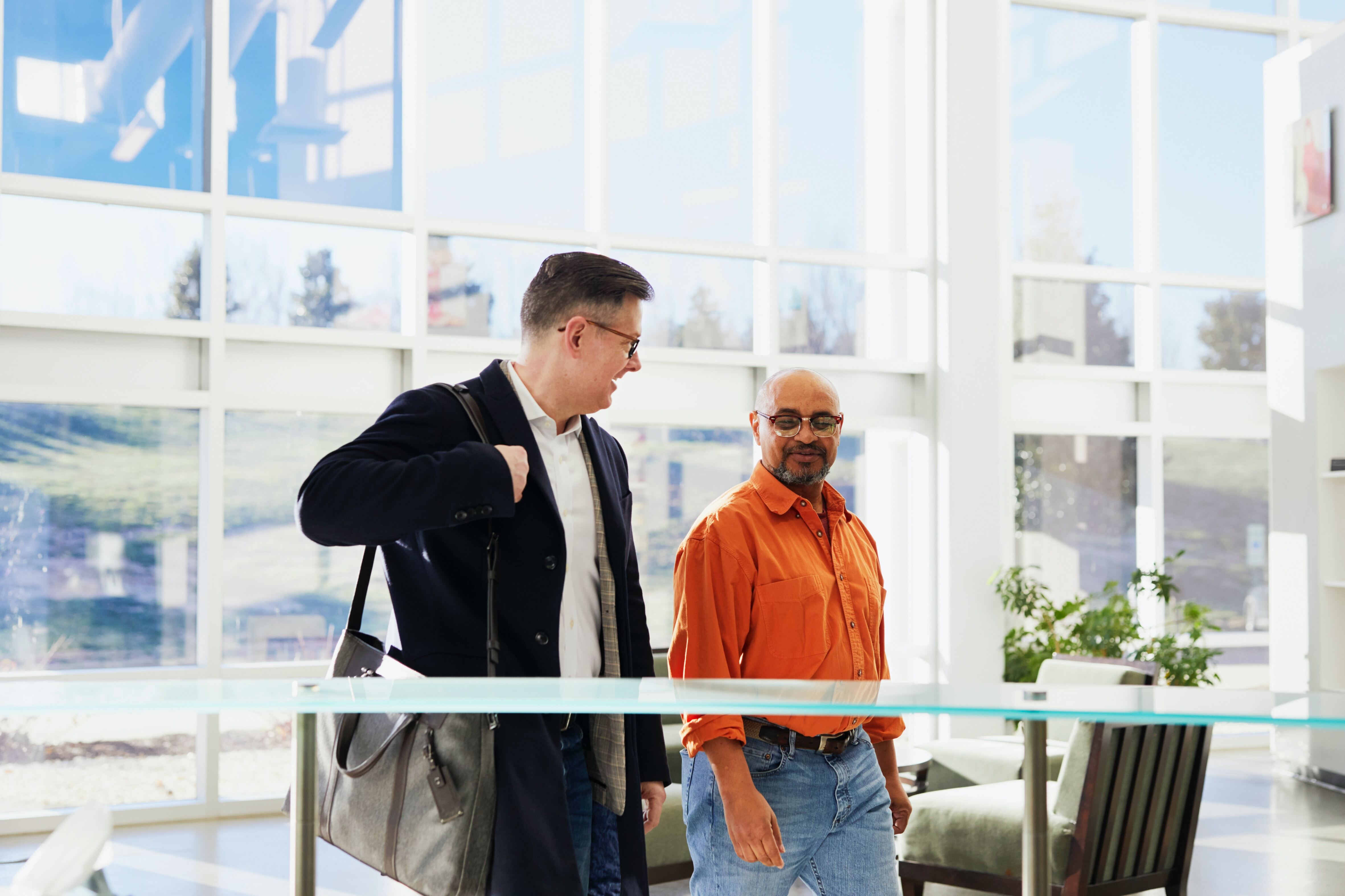 Two professionals walking and talking in a bright office space—representing open communication, collaboration, and client engagement