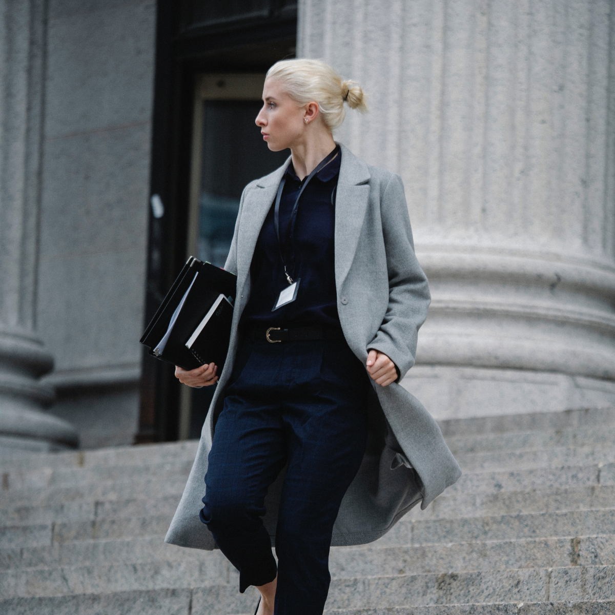 Public sector professional walking down government building steps with documents, representing leadership and accountability